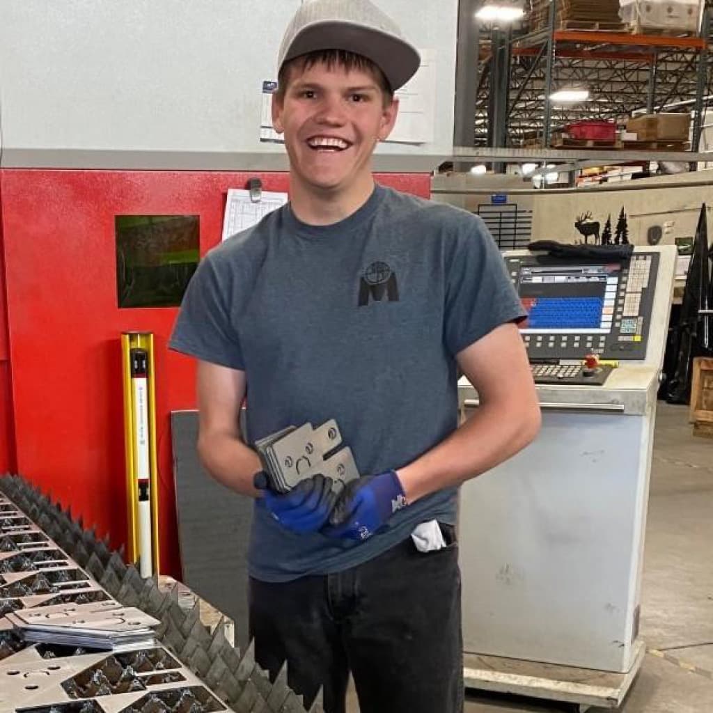 Jordan Warrick smiling as he works in electronics assembly